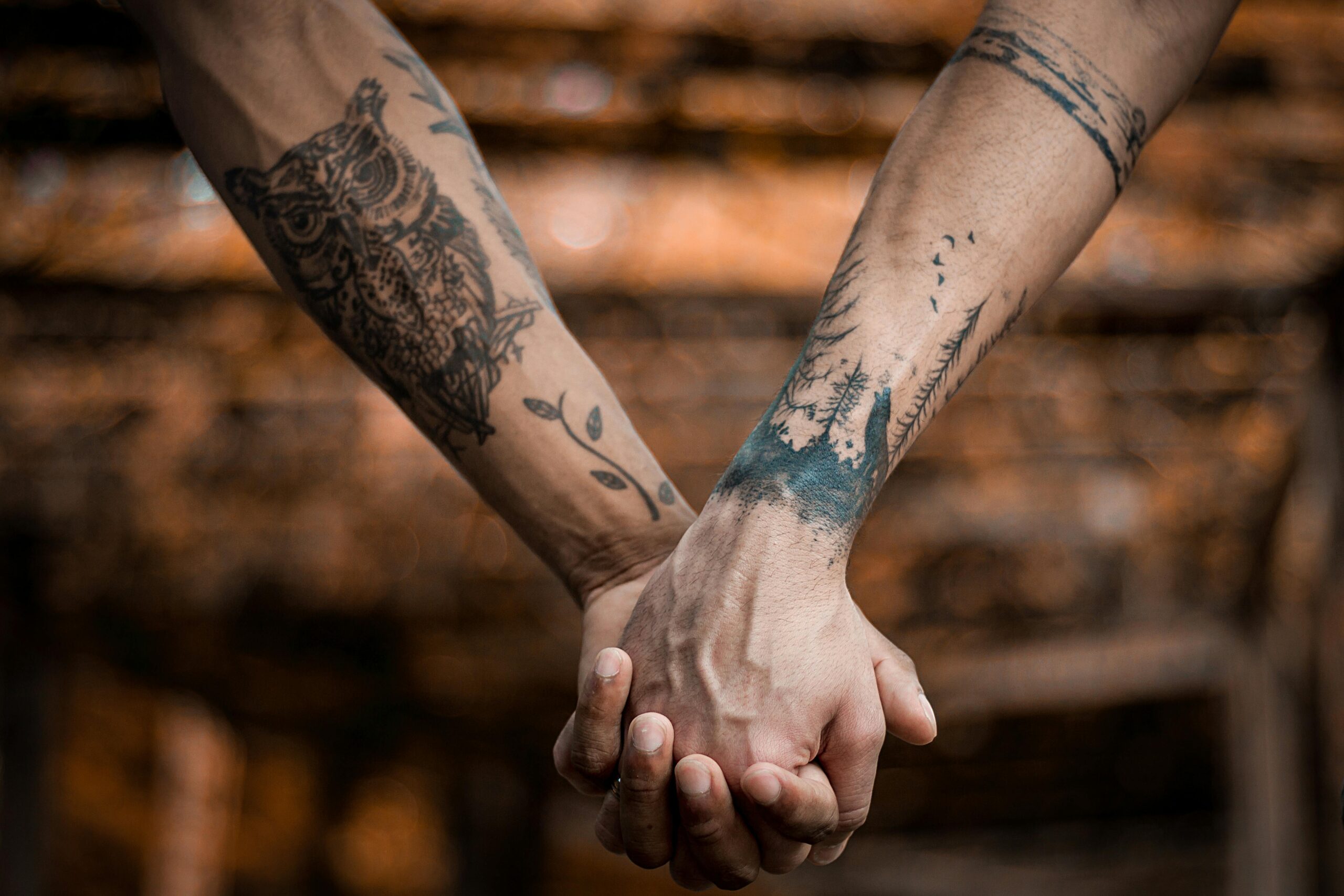 Deux bras avec des tatouages qui se tiennent par la main